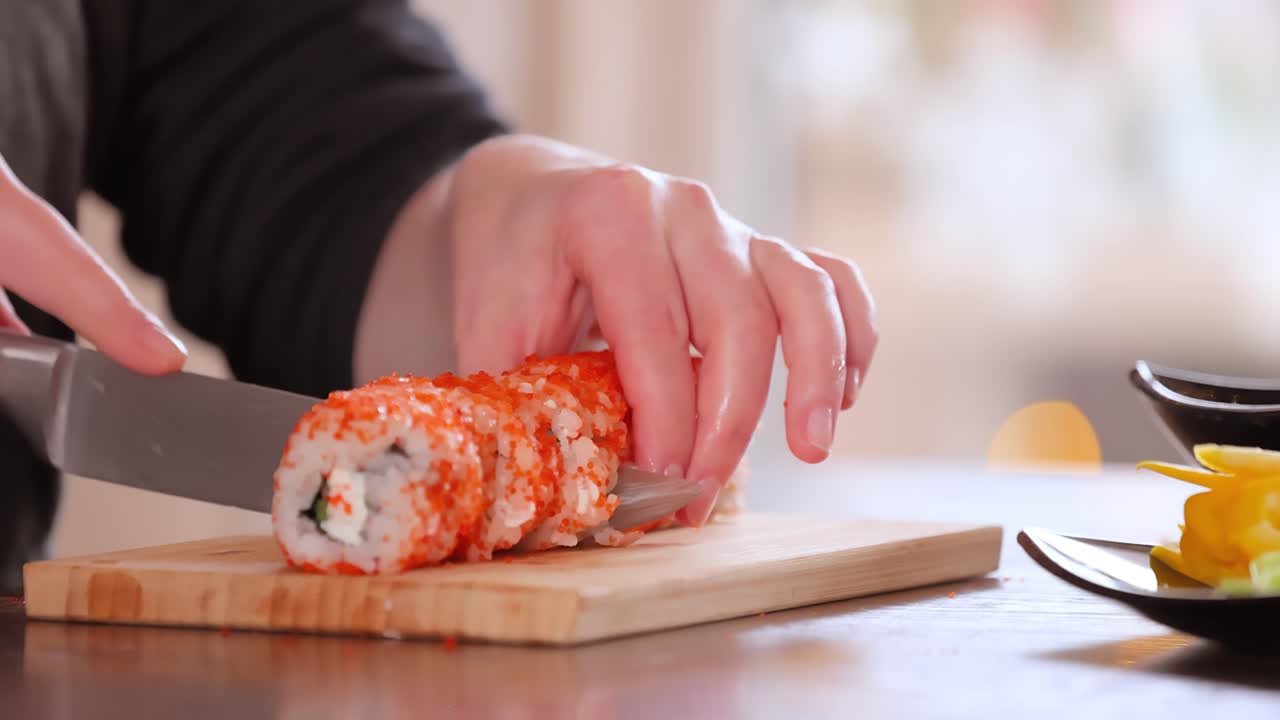 hacer sushi en la cocina de casa. manos de mujer enrollando sushi casero.