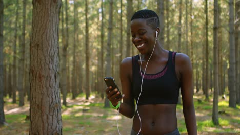female jogger using mobile phone in the forest 4k