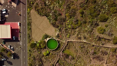 Grünes-Wasserreservoir-In-Der-Nähe-Der-Straße-Auf-Teneriffa,-Luftaufnahme-Von-Oben-Nach-Unten