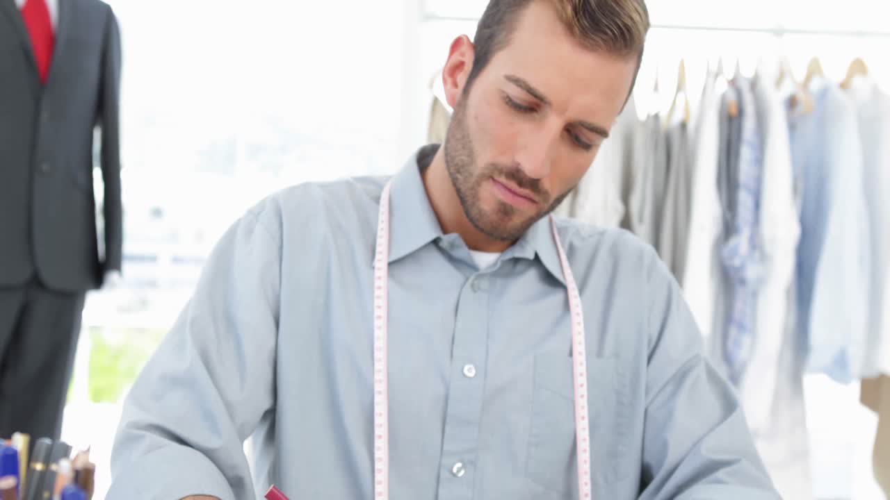 Handsome fashion designer sketching at his desk