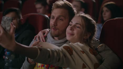 young people having fun at cinema. love couple making selfie photo in cinema