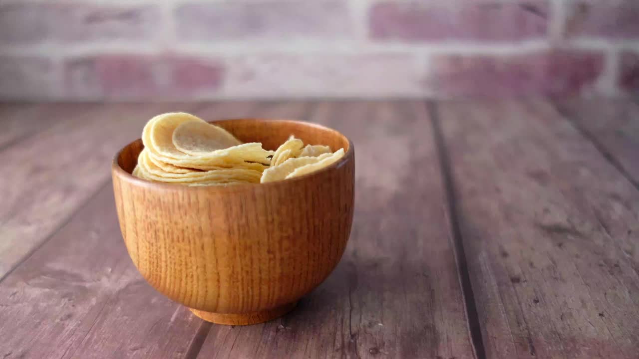 Hand picking chips from a wooden bowl