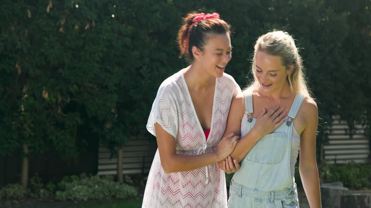 Two female friends walking outdoors, smiling and enjoying sunny day together