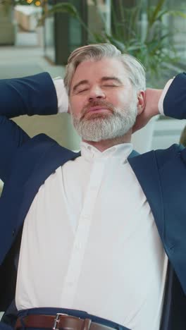 caucasian businessman taking break leaning on couch after working celebrating success at hotel lobby