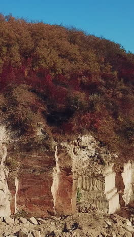 view of a large sand quarry with stones and forest. professional equipment works for the extraction of sand. camera motion left. vertical video
