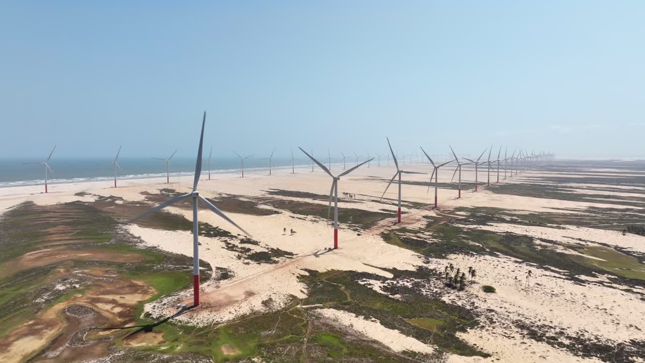 Wind turbines spin along gigh aerial of branching Parnaiba River delta system, Brazil, with sandbars and wide open water