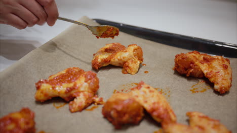 cubrir las alas de pollo con salsa picante usando una cuchara cocinar en casa, nutrición, ingredientes frescos, comida halal, preparación de comidas de fitness, ingesta calórica de carne marinada, dieta saludable y equilibrada consumo de carne