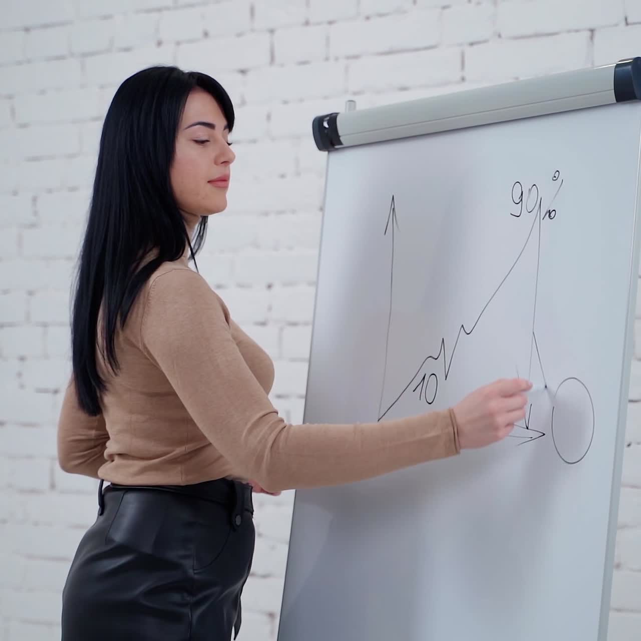 Young businesswoman writing on the whiteboard. Beautiful long-haired freelance girl writes with a marker on a board on the white studio background. Slow motion.
