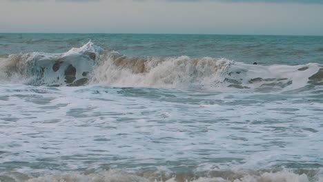 curvy, foamy waves crashing on the shore of the beach in slow-motion