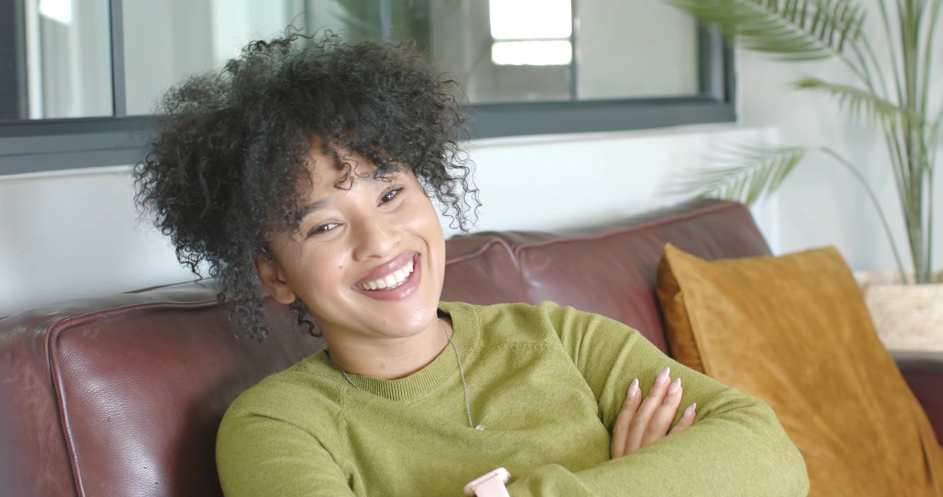 Donna afroamericana seduta sul divano di casa che reagisce a un segnale fuori campo sorridendo