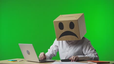 person with cardboard box head using smartphone in office