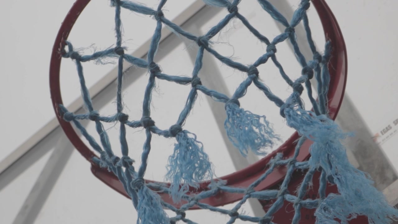 Vista dettagliata dal basso di un canestro da basket con rete blu usurata