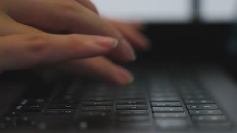 Slow-motion-side-on-shot-of-a-woman's-hands-wearing-rings-typing-on-a-keyboard