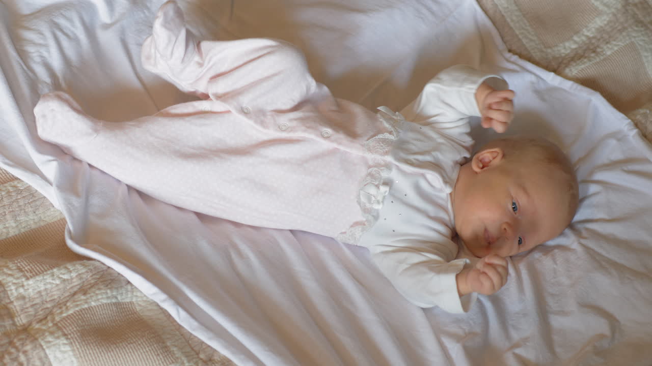 깨어있는 두 달 된 아기 소녀가 침대에 누워 있습니다.