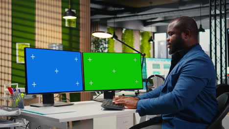 african american businessman examines reports with isolated dual monitors