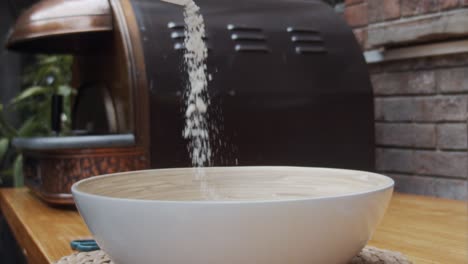 chef puts down the pizza flour into a deep plate