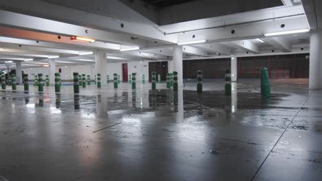 lights turn on at empty underground parking garage with water dripping from slab roof