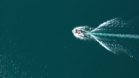 Aerial-top-down-dolly-in-of-a-group-of-people-sailing-in-a-motorboat-across-Puelo-Lake,-Patagonia-Argentina