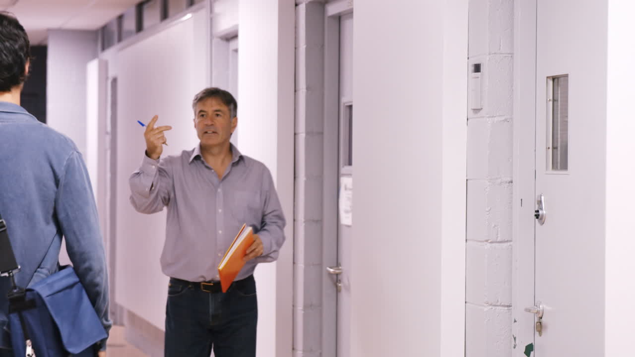 estudiante y maestro discutiendo en los pasillos.