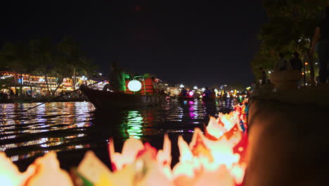 a stationary low-angle shot at the riverbank where the candle lanterns accumulated. the candle lanterns lined-up at the riverside.