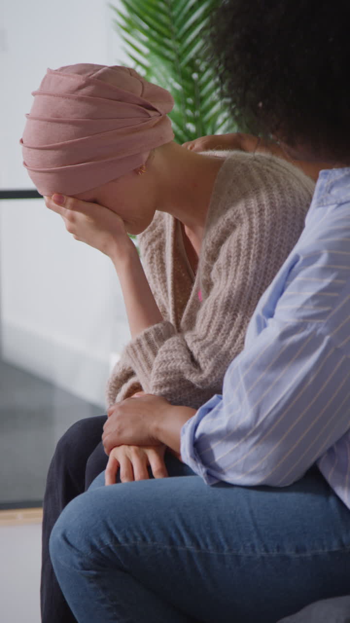 Vertical Video Of Upset Young Woman Patient Wearing Headscarf Receiving Chemotherapy Treatment For Breast Cancer Being Comforted By Female Patient 2