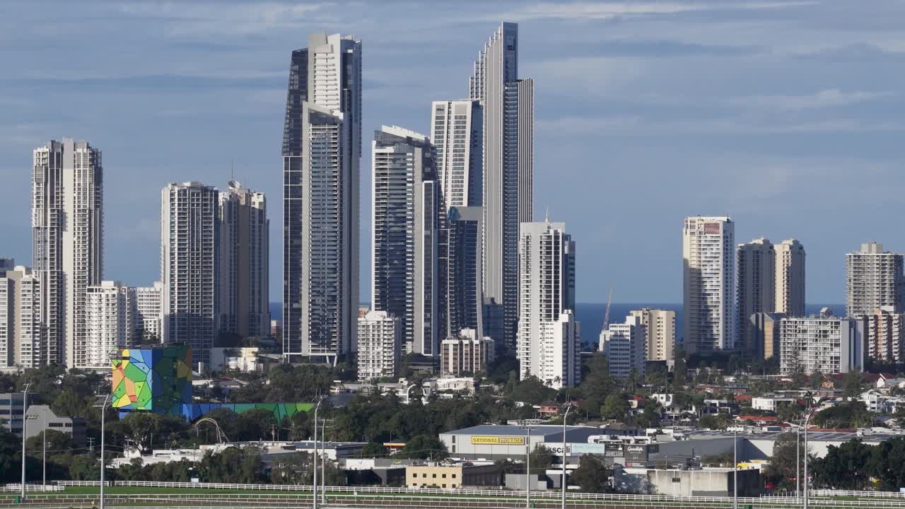 Aerial view of Gold Coast's iconic skyline with tall buildings under clear skies, captured in smooth drone motion