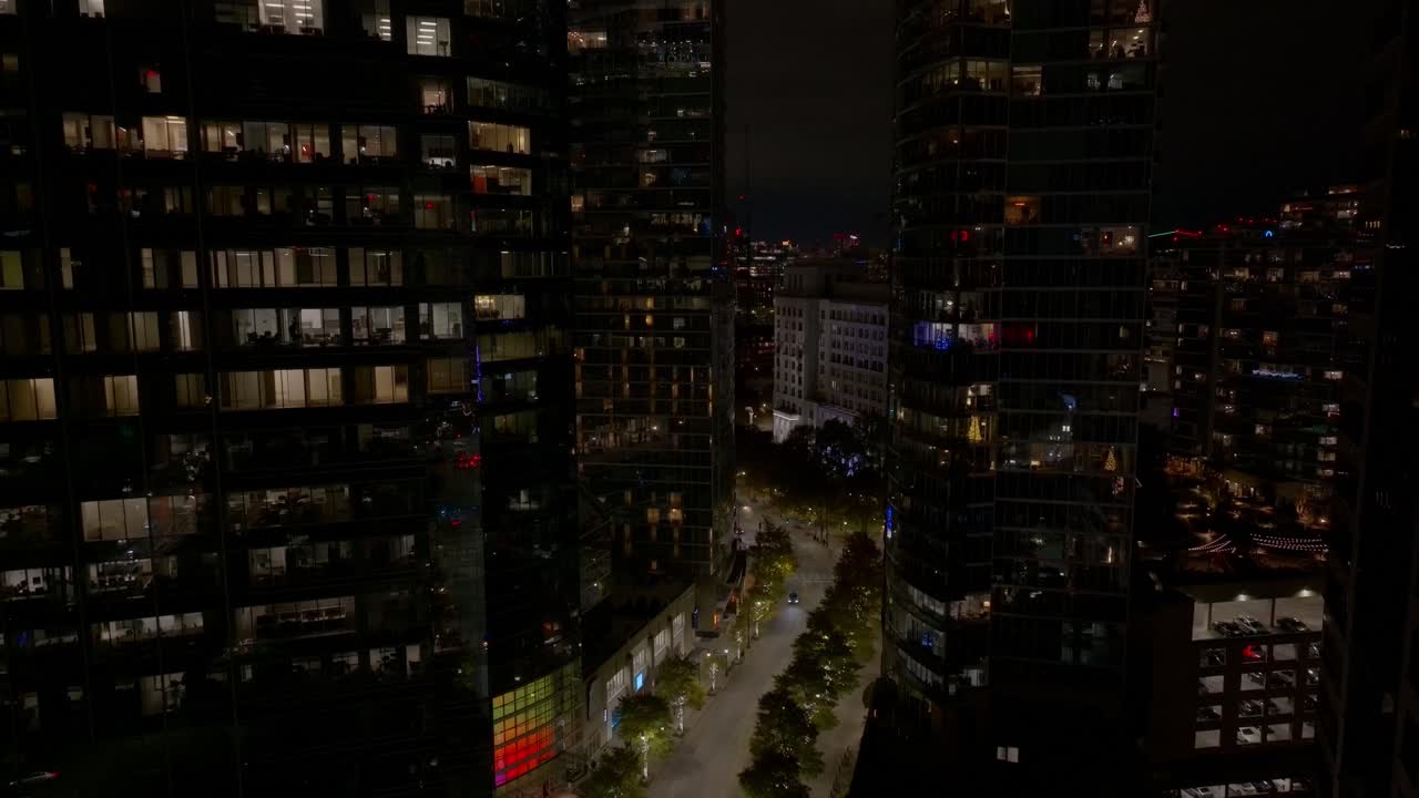 Atlanta Georgia Peachtree Street luxury condominium complex at night, commercial office buildings, skyline apartments glass walls revealing interiors with Christmas trees during holidays, Aerial