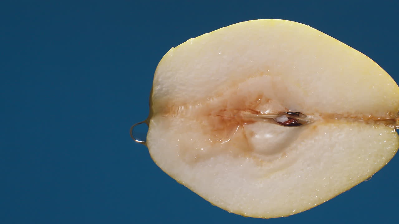 Detail of pear slice with water falling on the piece in slow motion