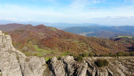 aerial: two hikers walking along a very narrow mountain crest in autumn season