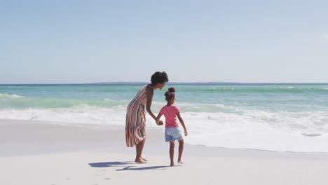 Lächelnde-Afroamerikanische-Mutter-Mit-Tochter,-Die-Am-Sonnigen-Strand-Spaziert