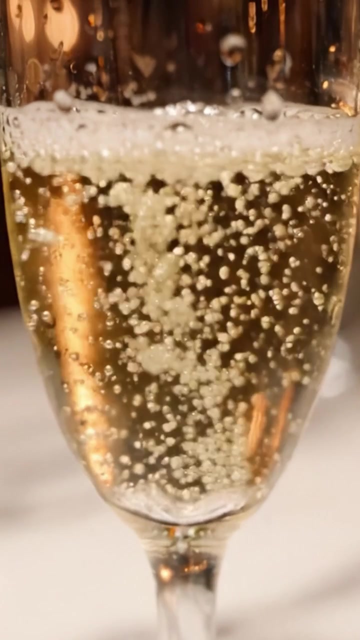 Una vista ravvicinata di champagne frizzante in un calice a flûte, che cattura le bollicine effervescenti e i dettagli eleganti di un brindisi celebrativo.