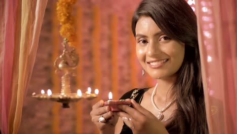 a close up of beautiful and traditional woman lighting a lamp during diwali festival.