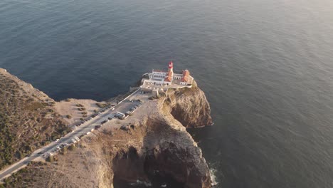 cinematic aerial seascape of cabo de sao vicente lighthouse on top of rugged cliff surrounded by atlantic ocean