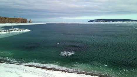 aerial view of percé rock in the winter with ice on the ocean