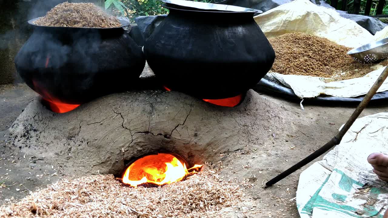 Burning bio fuel using a clay oven in rural parts of India. The heat is used to boil rice grain which helps hardening the rice inside bran