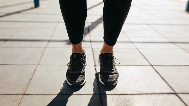 Leggingseihin pukeutuneet sääret ja jalat hyppivät puistossa, hyppynarun kulkiessa jalkojen alta kuntoilun vuoksi.