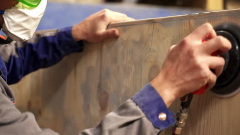 worker sanding wood plank in a workshop