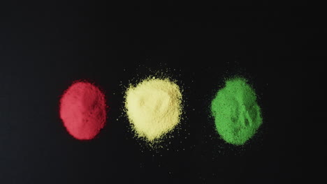 Video-of-red,-yellow-and-green-powders-with-copy-space-on-black-background