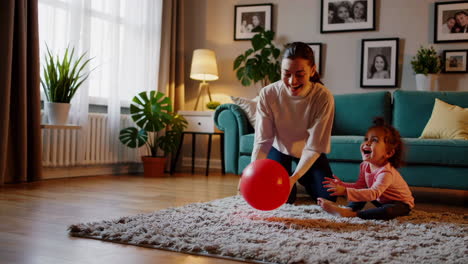 mother and baby play with red ball in living room