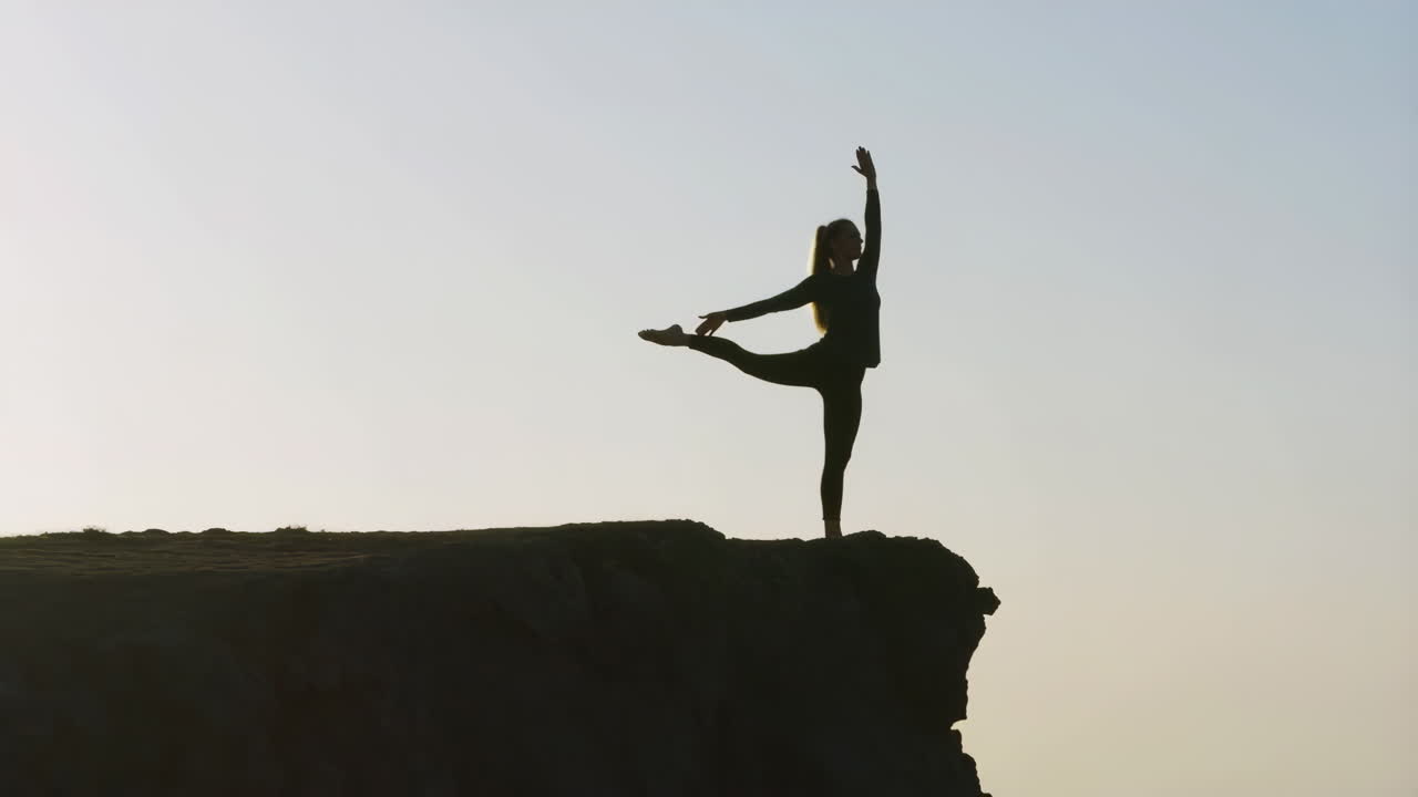 Woman Practicing Yoga or Dance Pose on Cliff Edge at Sunrise or Sunset