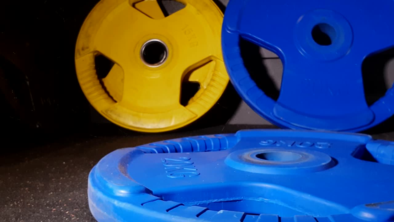 상업용 체육관에서 슬로우 모션으로 웨이트 플레이트가 떨어졌고 먼지가 많은 바닥으로 제대로 청소되지 않았습니다.