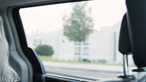 gray haired woman wearing suit and sitting in moving car