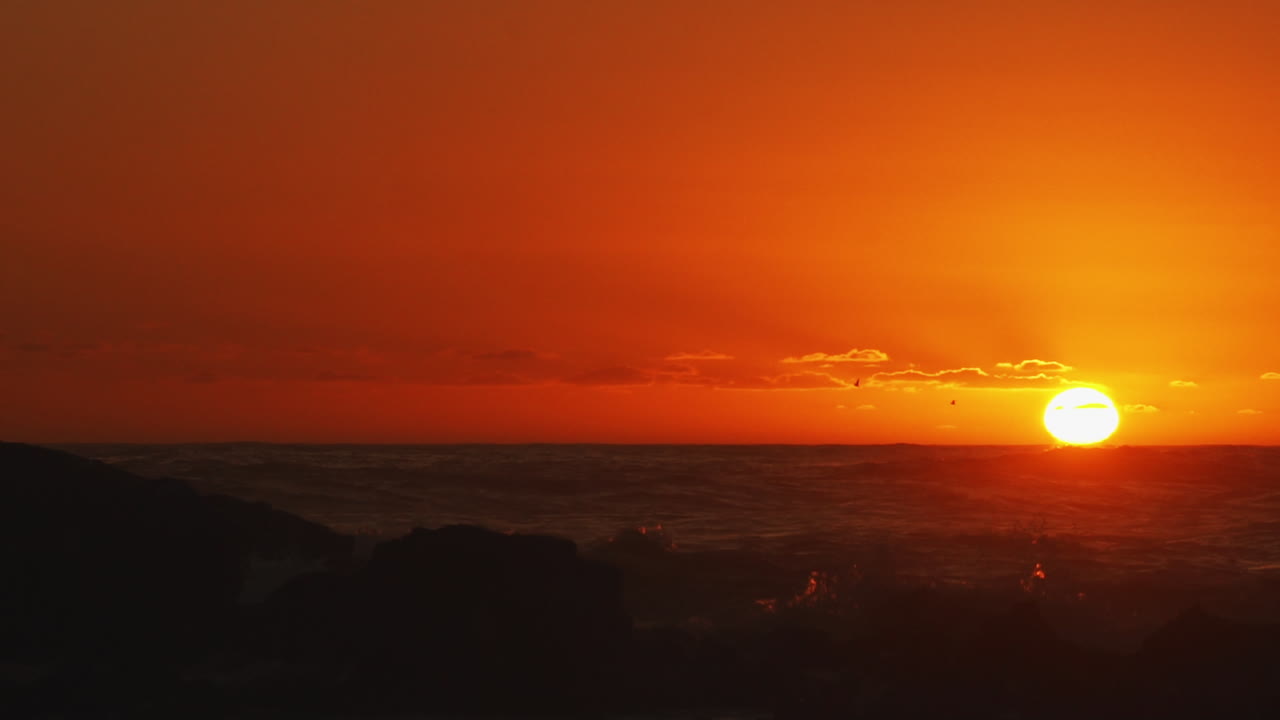 Goldener Sonnenuntergang über stürmischen Wellen, Vögel fliegen durchs Bild – Statische Aufnahme