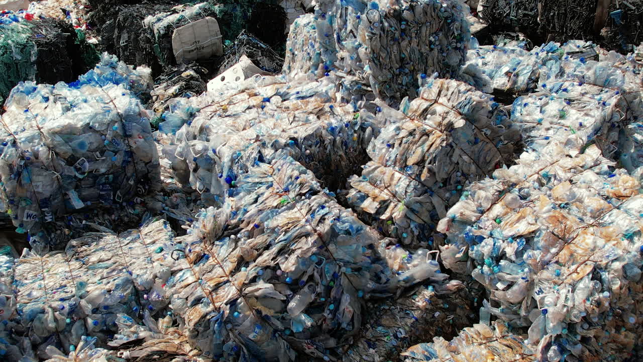 Multiple cubes of compressed plastic garbage at waste recycling factory in open air
