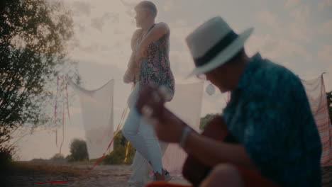 joven tocando la guitarra para una pareja bailando en la playa