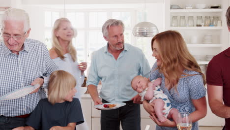 multi-generation family and friends gathering in kitchen for celebration party