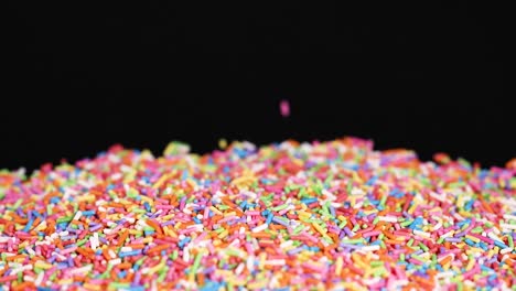 rainbow sprinkles cascade onto a black background