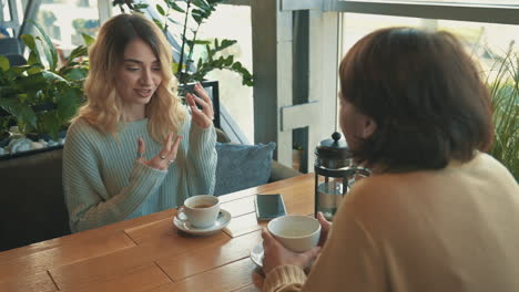 jóvenes amigas hablando y tomando una taza de té y café