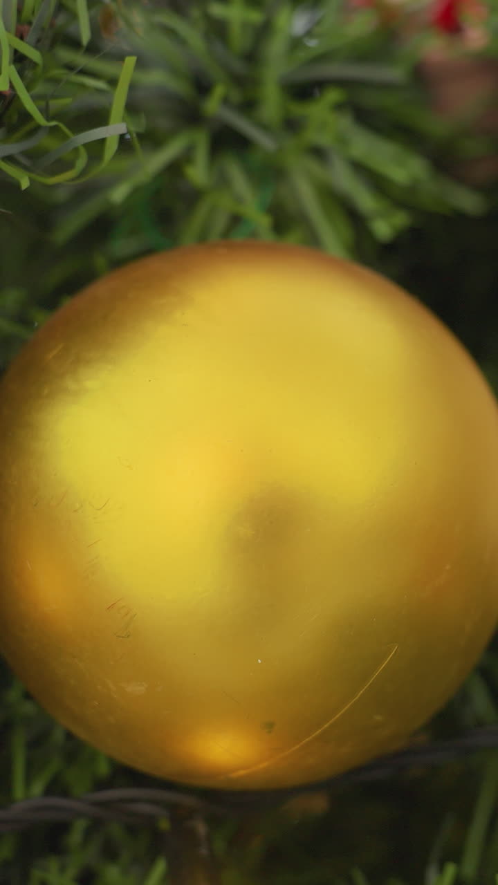 Close-up of Christmas tree with golden ornament and wooden decorations, sparkling lights, and soft bokeh effect filtering through branches