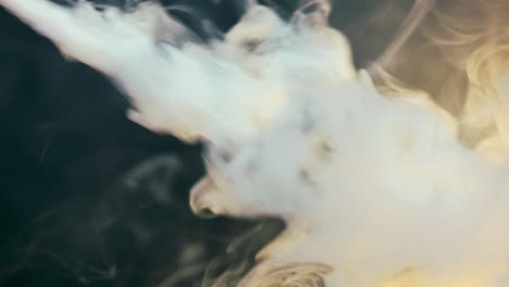 Abstract-pouring-out-of-white-smoke,-steam-in-the-dark-with-yellow-light-falling-on-it